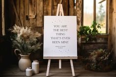 an easel with a quote on it next to two vases and a plant