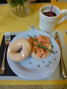 a white plate topped with donuts next to a cup of coffee and spoons