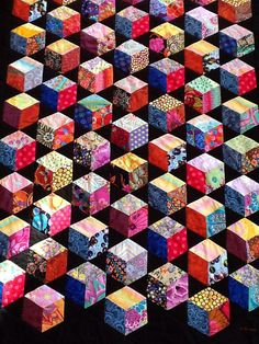 a quilt made up of many different colored cubes on black fabric with white polka dots