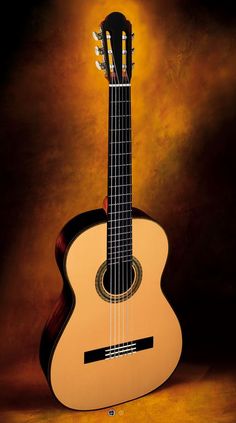 an acoustic guitar sitting in front of a dark background