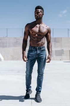 a man with no shirt standing on concrete