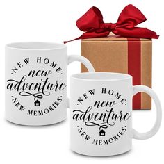 two coffee mugs are next to a gift box with a red bow on it