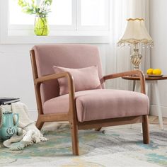 a pink chair sitting on top of a rug next to a table with a vase