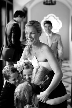 black and white photograph of a woman hugging her two children while three other people look on