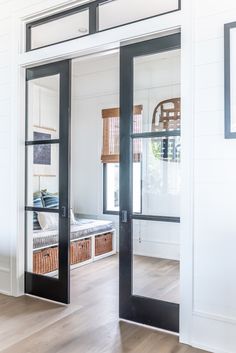 an open door leading to a bedroom with white walls and wood floors, along with two wicker baskets on the floor