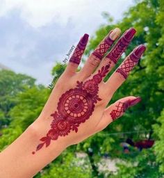 a hand with henna on it and trees in the background