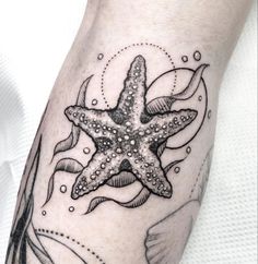 a starfish tattoo on the left arm with an ocean scene in the middle and fish around it