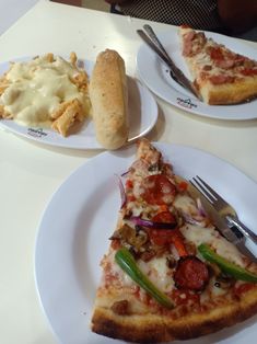 two slices of pizza sitting on top of white plates