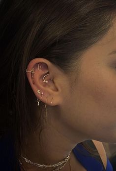 a close up of a person with ear piercings on their ears and wearing gold jewelry