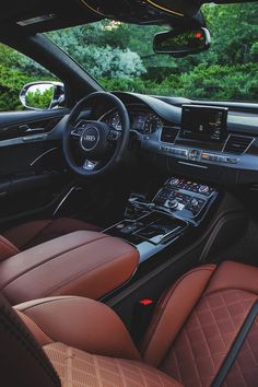 the interior of an audi car with brown leather seats and dashboard controls, trees in the background