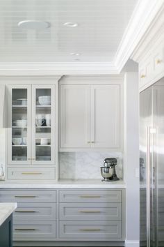 a kitchen with white cabinets and marble counter tops