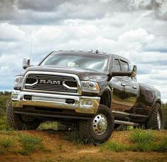 a black ram truck parked on top of a dirt road next to a body of water