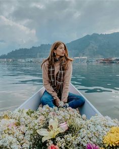 a woman sitting in a boat filled with flowers