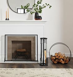 a fireplace with a mirror and firewood in front of it on a wooden floor