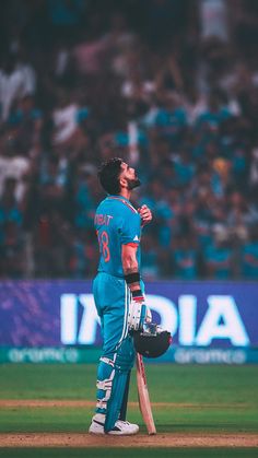 a man standing on top of a green field holding a cricket bat in his hand