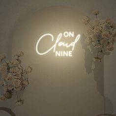 a neon sign that says on cloud nine with flowers in vases next to it