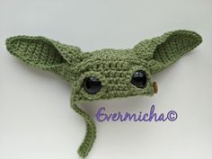 a crocheted green hat with big eyes and ears is shown in front of a white background