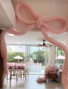 a room decorated with pink balloons and bows