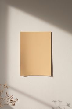 an empty piece of paper hanging on the wall next to a vase with dried flowers