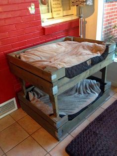 a dog bed made out of pallets in front of a brick wall and window