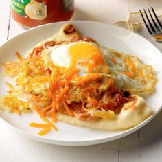 an omelet with meat and cheese is on a plate next to a fork