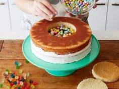 a person is decorating a cake with candy and sprinkles on it