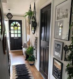 a hallway with black doors and pictures hanging on the wall next to it's entrance