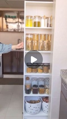 a woman standing in front of a kitchen with lots of food on the shelves and she has her arms out