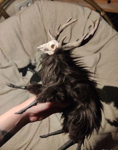 a person holding a fake animal with horns and claws on it's head, in their hand