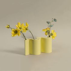 two yellow vases with flowers in them on a gray surface, one is empty