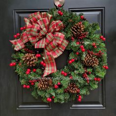 a christmas wreath with red berries and pine cones