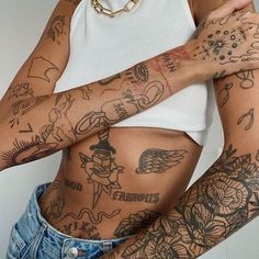 a woman with many tattoos on her body and arms is posing for the camera in front of a white wall