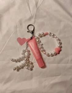 a pink toothbrush and some pearls on a white sheet with a keychain