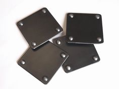 four square black metal plates with rivets on them