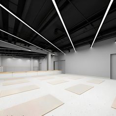 an empty room with lots of white mats on the floor and some lights above it