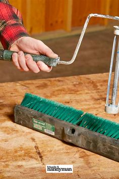 a person using a brush to clean a piece of wood with a hand held tool