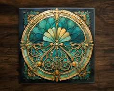 an intricately designed piece of art on a wooden surface with gold and green accents