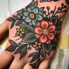 a woman's hand with flowers and leaves painted on the inside of her palm