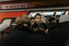 a group of people standing in front of a red subway car that says the world is your