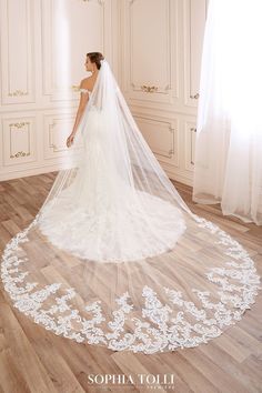 a woman in a wedding dress standing on a wooden floor with a veil over her head