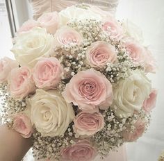 a bride holding a bouquet of pink and white roses