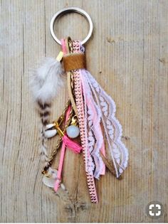 a key chain with feathers and beads hanging from it's side on a wooden surface