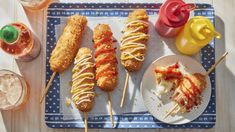 several different types of food are on a blue and white tray next to cups with drinks