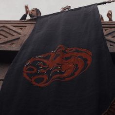 some people are standing on top of a building and one is holding up a black flag