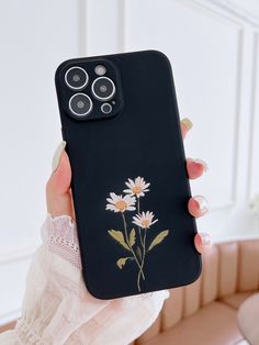 a woman is holding up her phone case with flowers on the front and back cover