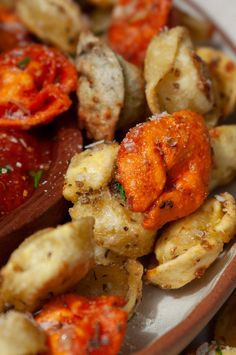 a plate full of roasted vegetables with sauce on top and seasoning next to it