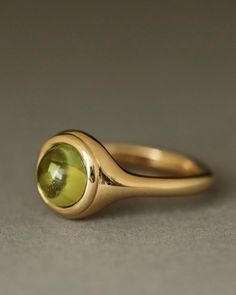 Description For the August birthdays and those who love the gorgeous olive green of peridot, meet The Duchess. Modeled after The Monarch, this sweet ring was designed with our mom in mind — a woman who prefers beauty, simplicity, and quality in more petite forms. Peridot is a variety of olivine, and is one of only two gems formed not in the earth's crust, but in the molten rock of the upper mantle. It is believed to carry the gift of "inner radiance," sharpening the mind and opening it to new le August Birthdays, Sweet Ring, Luxury Jewelry Brands, Peridot Jewelry, The Monarch, Bezel Ring, How To Apologize, Coin Ring, Peridot Ring