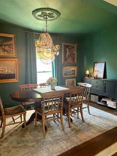 a dining room with green walls and pictures on the wall