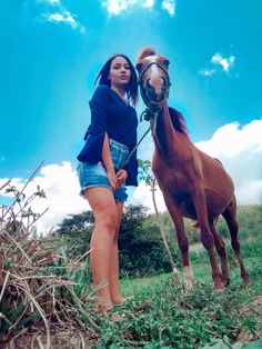 a woman standing next to a brown horse