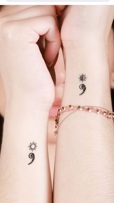 two people with matching tattoos on their arms and wrist, one is holding the other's hand